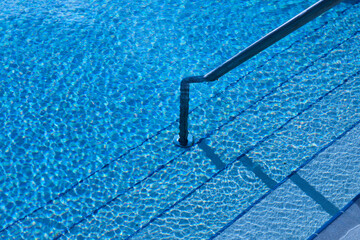 Texture and pool surface. Transparent and blue water. Access stairs and depth marks.