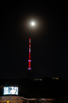 Yerevan, Armenia - September 28, 2023: full moon over red illuminated TV tower in Yerevan city at night. High lattice tower was built in 1977 on Nork Hill near downtown of Yerevan