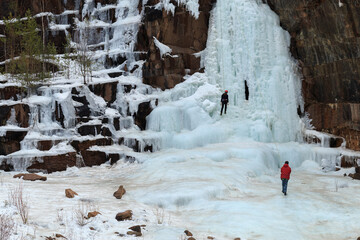 athletes - climbers train on a glacier, young climbers climb an icy rock with a safety rope