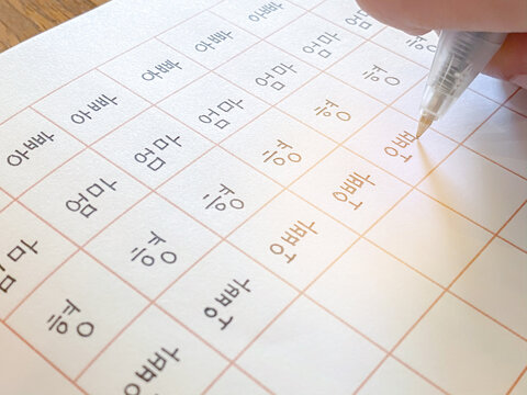 Close up Hand writing korean alphabet and learn foreige language , Apa mean father, Omma mean mother, Hyung mean brother, Oppa mean brother, on warm wooden table in holiday as a hobby