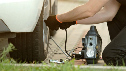 Man Inflates Tire With Portable Pump As Mechanic