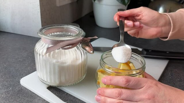 hands of woman pouring granulated sugar on lemon slices on kitchen counter. High quality 4k footage, slow-mo zoom in