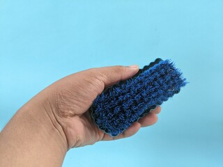 Hand holding a clothes washing brush made of plastic