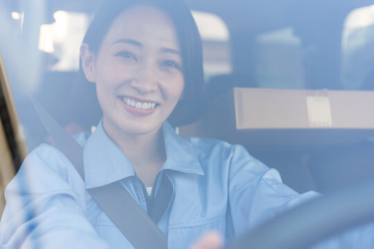ガラス越しに笑顔で運転する女性