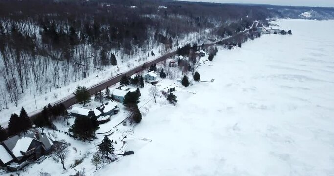 Aerial Shot Of Houses Near People Riding Snowmobiles Amidst Trees During Winter - Houghton, Michigan