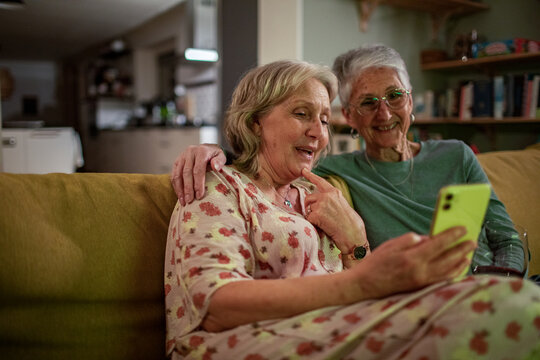 Senior lesbian couple sharing a joyful moment with a smartphone