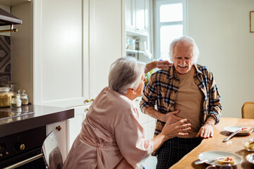 Woman comforting a distressed senior man in the kitchen
