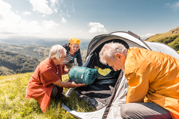 Senior friends setting up a tent amidst breathtaking nature