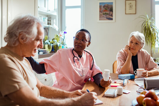 Compassionate nurse discussing health matters with an elderly couple