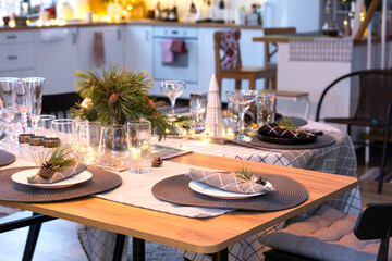 Serving a festive table with plates, forks, knives, napkins, glasses close-up in the modern interior of a loft house decorated for Christmas and New Year. Waiting for guests for a festive dinner