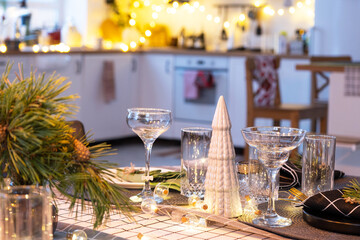 Serving a festive table with plates, forks, knives, napkins, glasses close-up in the modern interior of a loft house decorated for Christmas and New Year. Waiting for guests for a festive dinner