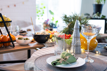 Serving a festive table with snacks, salads and goodies close-up in the modern interior of a loft house decorated for Christmas and New Year. Waiting for guests for a festive dinner