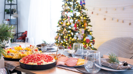 Serving a festive table with snacks, salads and goodies close-up in the modern interior of a loft house decorated for Christmas and New Year. Waiting for guests for a festive dinner