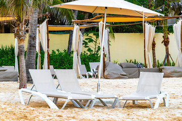 Palapa thatched roofs palms parasols sun loungers beach resort Mexico.
