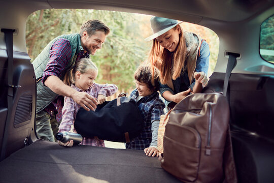 Joyful family packing their car for a road trip
