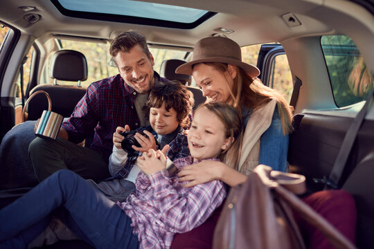 Family Bonding Over Photos During A Road Trip Break