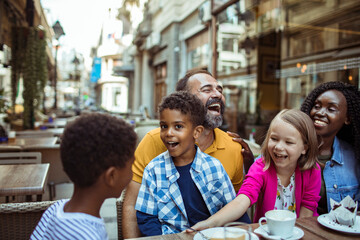 Fototapeta na wymiar Stepfamily sharing joyful moments at an outdoor cafe in the city