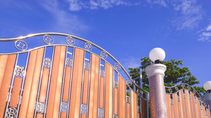 Low angle view of modern stainless steel and wooden sliding gate door with round lamp on mosaic...