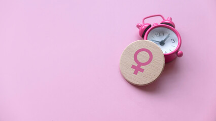 Menopause concept. Women symbol over a watch. Healthcare and medical for women. Pink background with copy space. - obrazy, fototapety, plakaty