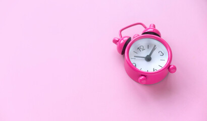 Pink alarm clock over a pink background.