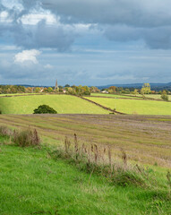 Looking across typical rolling English Cotswold landscape towards a church in the middle distance - 669150042