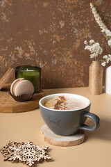 A cup of warm cocoa with a macaroon and cozy winter decor. Warm drink for cold weather
