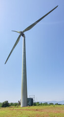 portrait full view of single wind turbine with blue clear sky