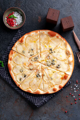 Pizza with pear and gorgonzola cheese on a dark background. Top view