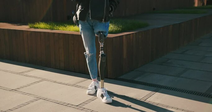 Close up shot of young woman with prosthetic leg walking in city. Woman with bionic leg. Woman with leg prosthesis equipment