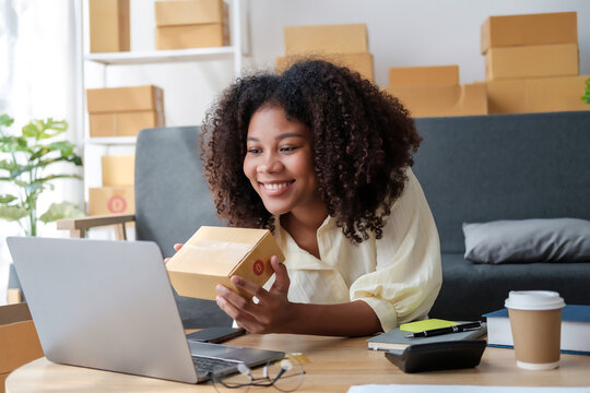 African American business woman working at warehouse preparing SME package box for delivery at small business home office.