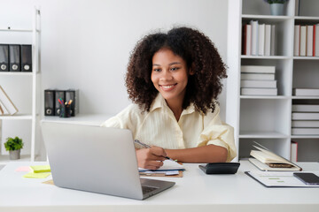 African American businesswoman sitting at the desk in front of the laptop and thinking.