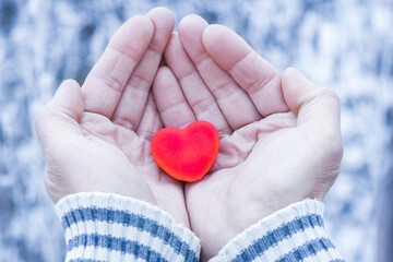 A In the hands of the heart in winter on the road in the park travel background