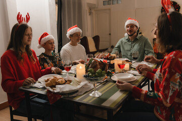 Beautiful happy family gathered around the table, having Christmas dinner, enjoying their time...