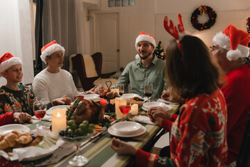 Beautiful happy family gathered around the table, having Christmas dinner, enjoying their time...
