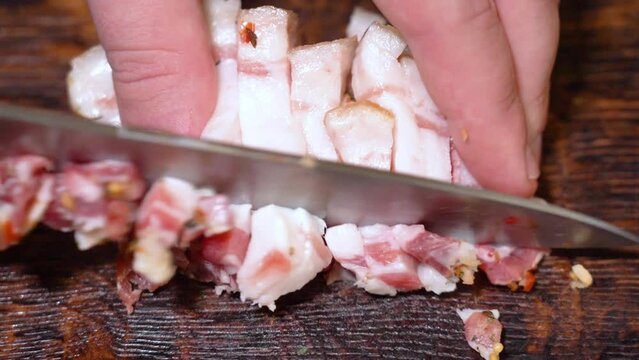 Slicing of salted pork fatback on cutting board, close-up. Ukrainian traditional food - salo	
