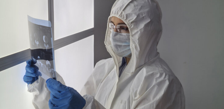 COVID-19 or 2019-nCoV Doctor in protective PPE suit taking x-ray of lungs of patient with coronavirus pneumonia