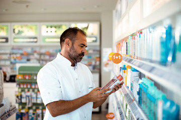 A pharmacist examines a product closely amidst the pharmacy shelves