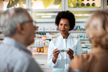 Joyful pharmacist engages in a lively conversation with senior customers