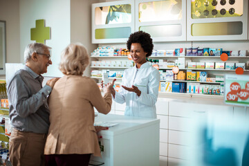 Joyful pharmacist engages in a lively conversation with senior customers