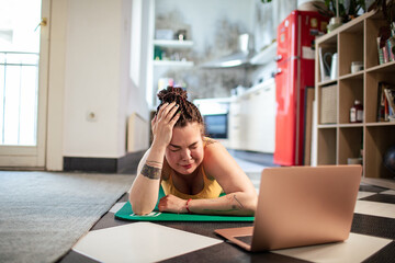 Focused woman follows an online yoga session in her kitchen