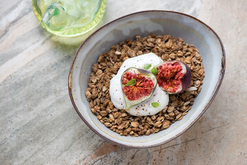 Bowl of granola served with fresh figs and greek yogurt, elevated view on a grey granite background, horizontal shot
