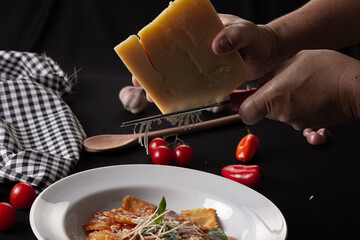 Italian pasta spaghetti on a white plate surrounded by various ingredients and kitchen utensils on a black table
