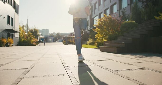 Young female student with prosthetic leg walking in university campus. Woman with bionic leg. Woman with leg prosthesis equipment