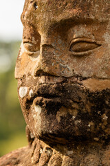 Close-up of the face of one of the figures of geurreros guarding the access to one of the gates to the temple of Bayon, in the ancient city of Angkor, Cambodia