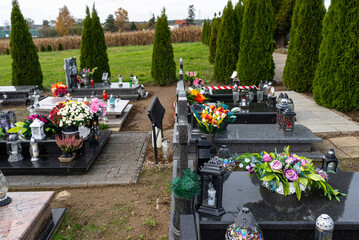 Artificial and real flowers and lit candles lying on the tombstone in the cemetery.