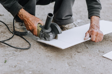 A man, a worker, cuts off plastic material for insulation with a grinder, an electric cutter.