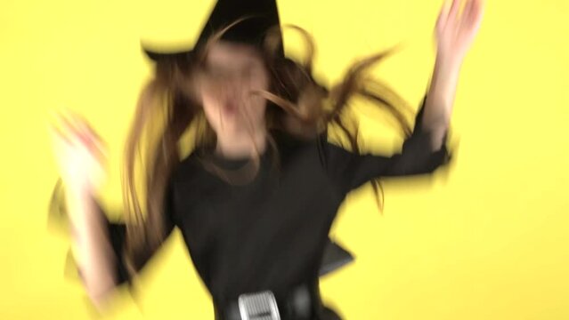 A little girl on a yellow background shows emotions, the concept of the holiday Halloween
