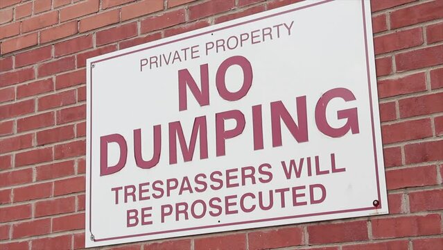 private property no dumping trespassers will be prosecuted horizontal rectangle sign on brick wall, red white, close up