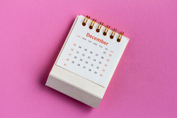 December monthly desk calendar for 2023 on pink background.
