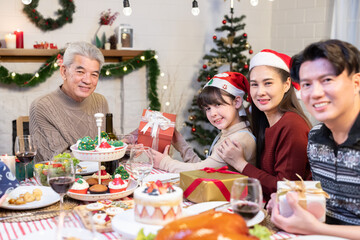 Family celebrating Christmas party dinner at home with the activity of giving gifts to family members